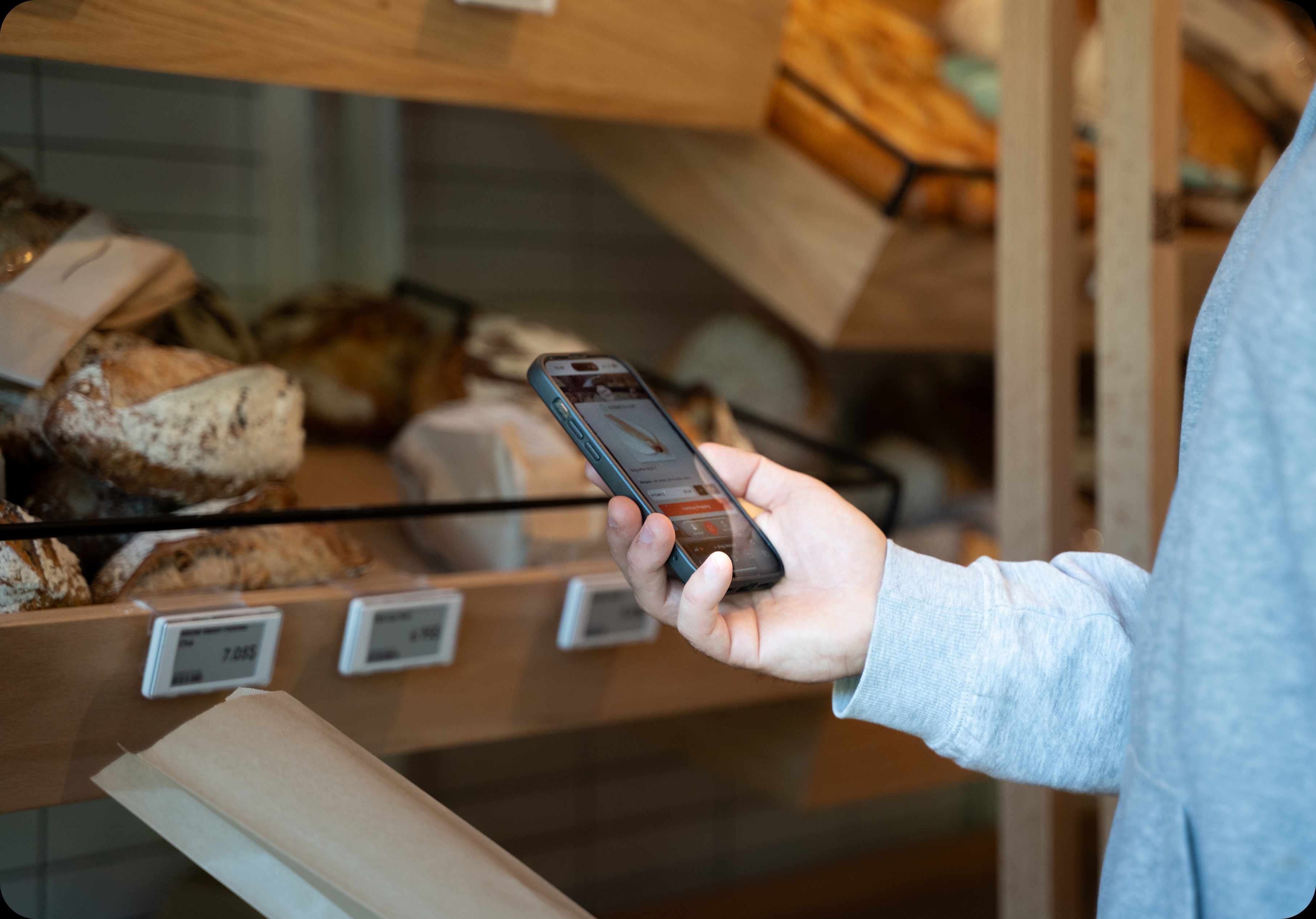 Person using a smartphone to interact with a smart shelf label in a bakery